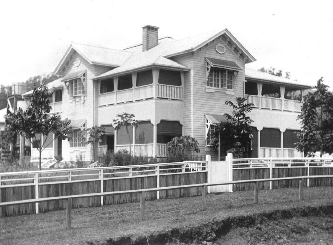 Two storey white old Queenslander style building with verandas on both floors